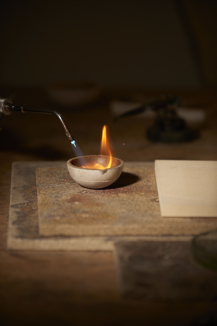 On voit la créatrice Louise Vurpas pour Bijouterie Fine en train d'utiliser son chalumeau pour fondre une pépite d'or - Bijouterie Joaillerie, sur-mesure
