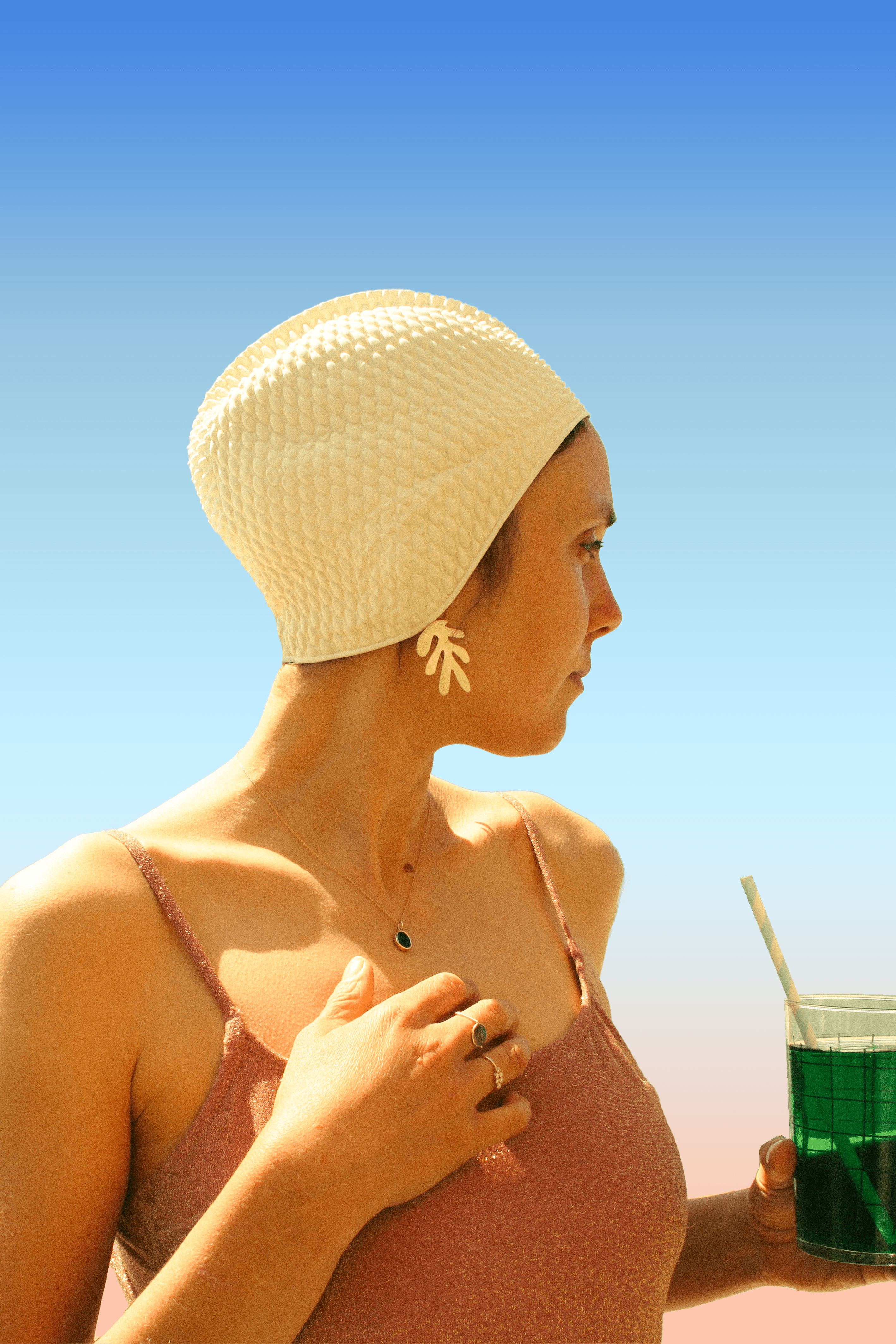 On voit une baigneuse style années 20, qui boit une menthe à l'eau, et qui porte des bijoux Louise Vurpas pour Bijouterie Fine - Bijouterie-joaillerie, sur-mesure