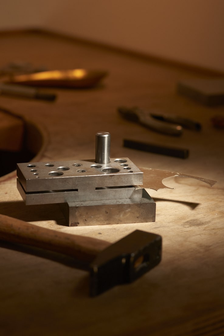 On voit l'établi de la créatrice Louise Vurpas pour Bijouterie Fine et ses outils dont une plaque d'argent - Bijouterie Joaillerie, sur-mesure